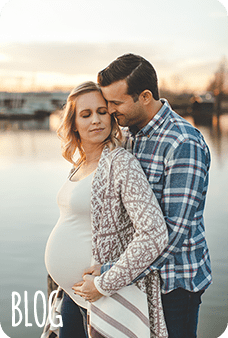 Pregnant woman with husband by lake at sunset