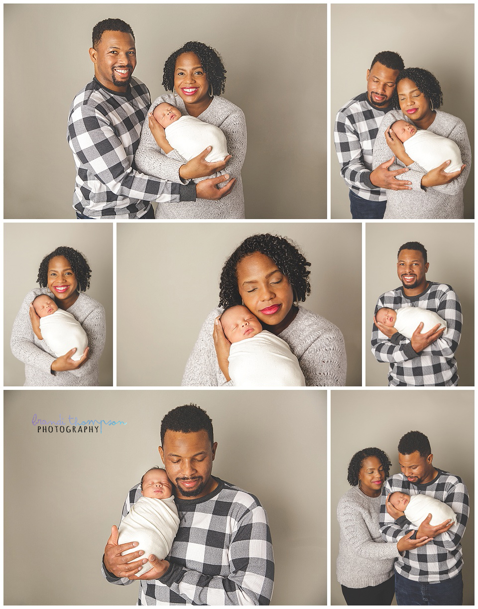 Black family with newborn baby on a warm gray background, they are wearing black, white and gray and baby is wrapped in gray